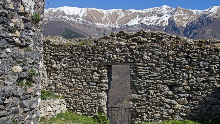 Ruderi in pietra di Triora con le Alpi innevate